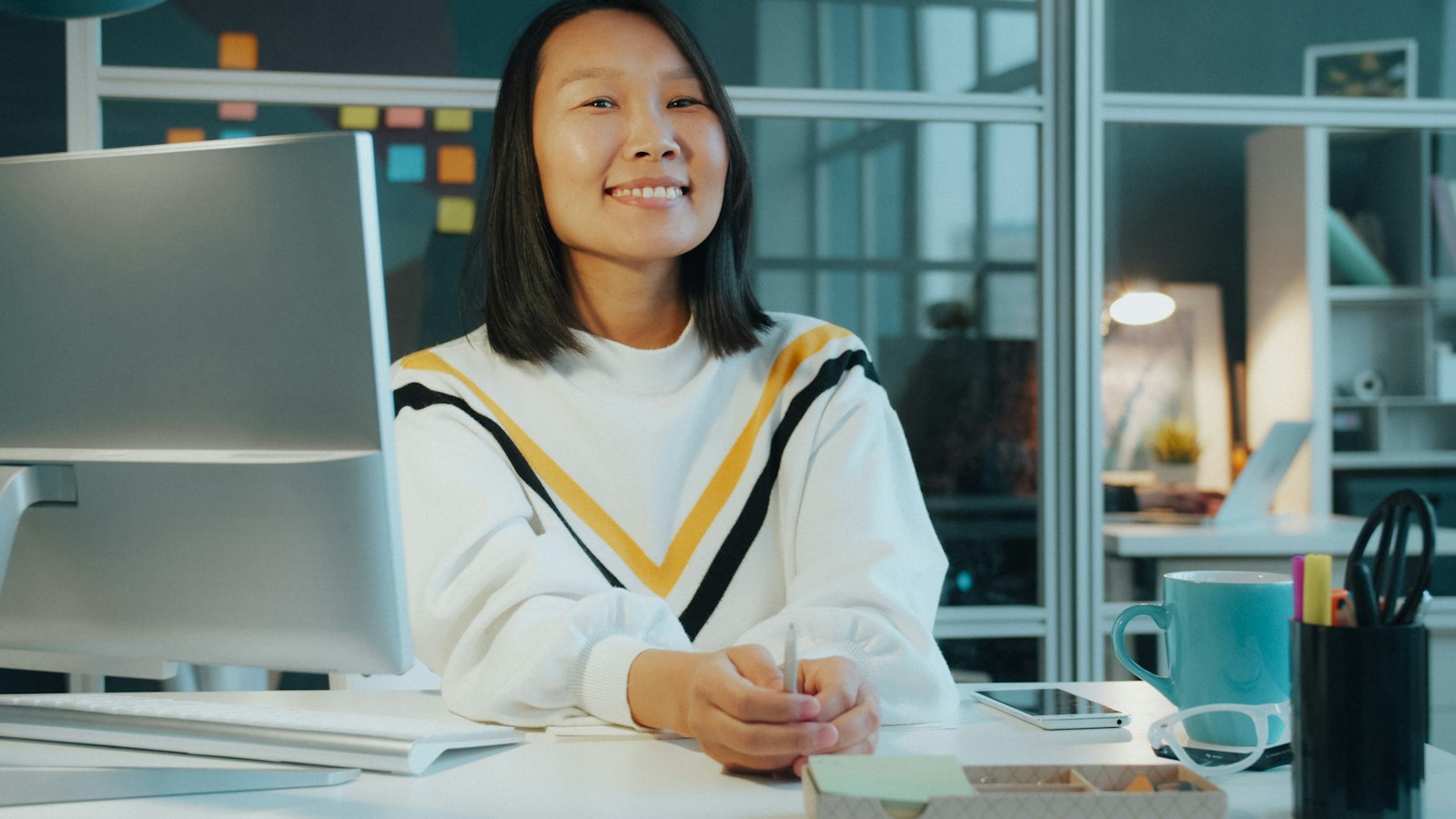 Empreendedora sorrindo em um escritório claro e moderno, ao lado de anotações do dia a dia da loja