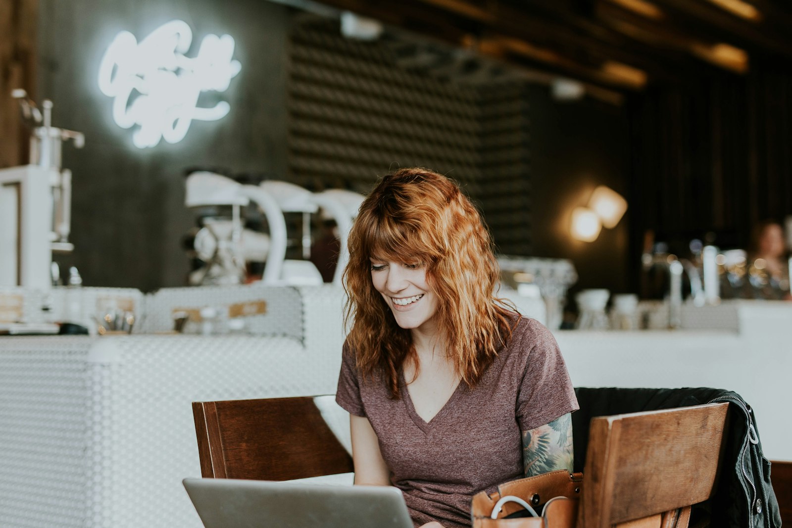 Empreendedora sorrindo em um café, trabalhando no laptop