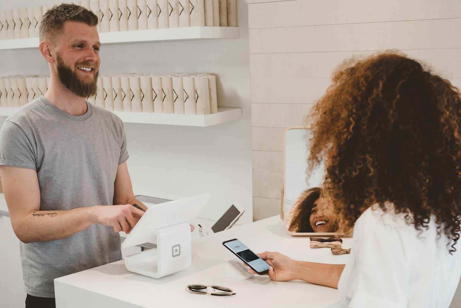 Vendedor sorrindo enquanto processa um pagamento no ponto de venda