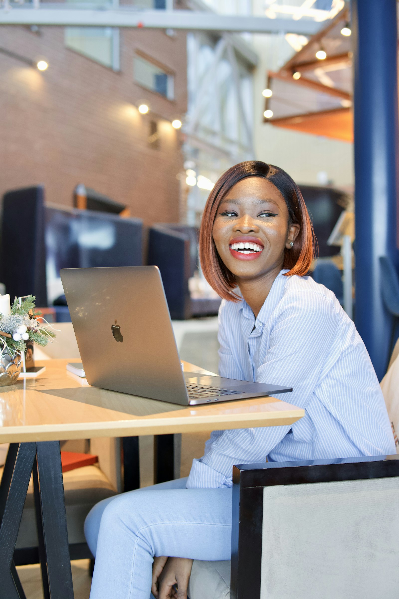 Empreendedora sorrindo em um café, com o MacBook aberto, tranquila com a adequação à Reforma